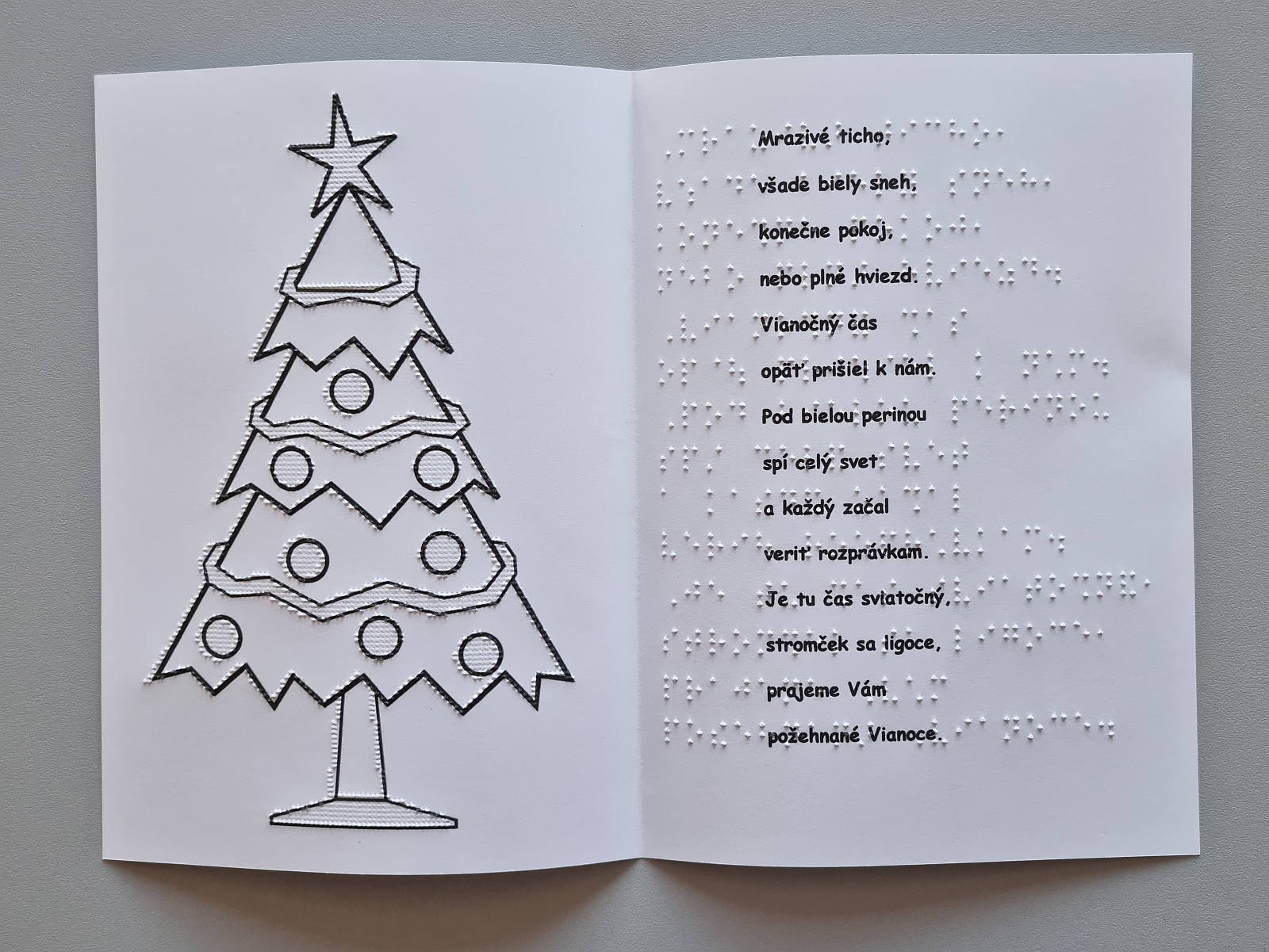 Vianočná pohľadnica, na obrázku je ozdobený vianočný stromček. Text v braili aj čiernotlači.